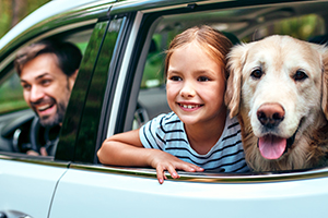 Father, daughter and dog riding in a car.