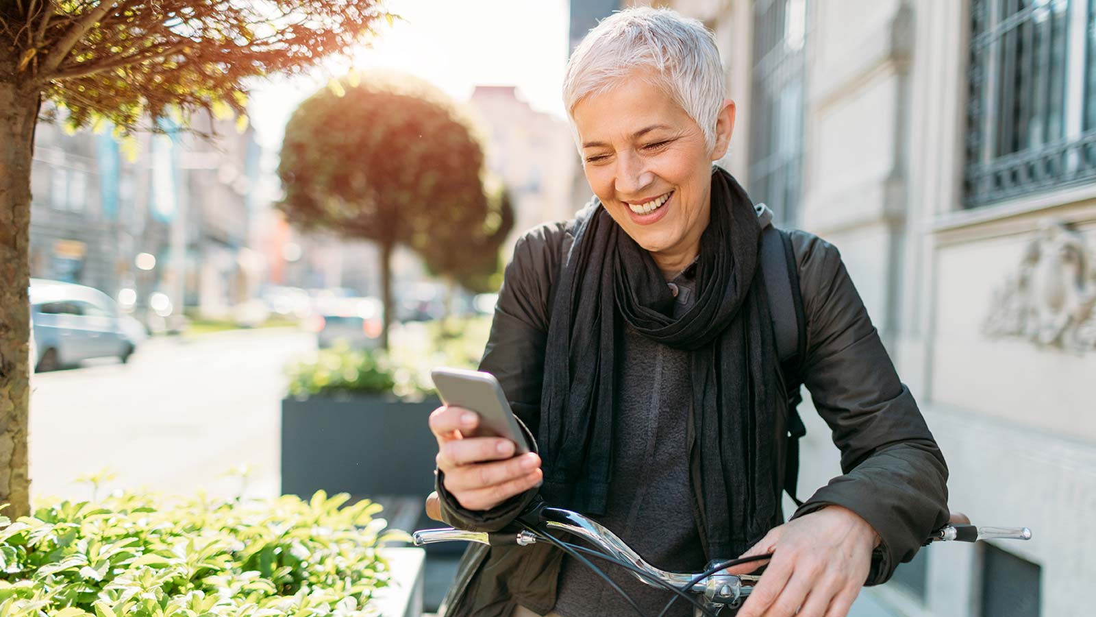 Older woman sitting on a bike looking at her phone.