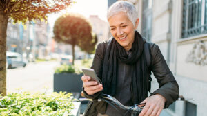 Older woman sitting on a bike looking at her phone.