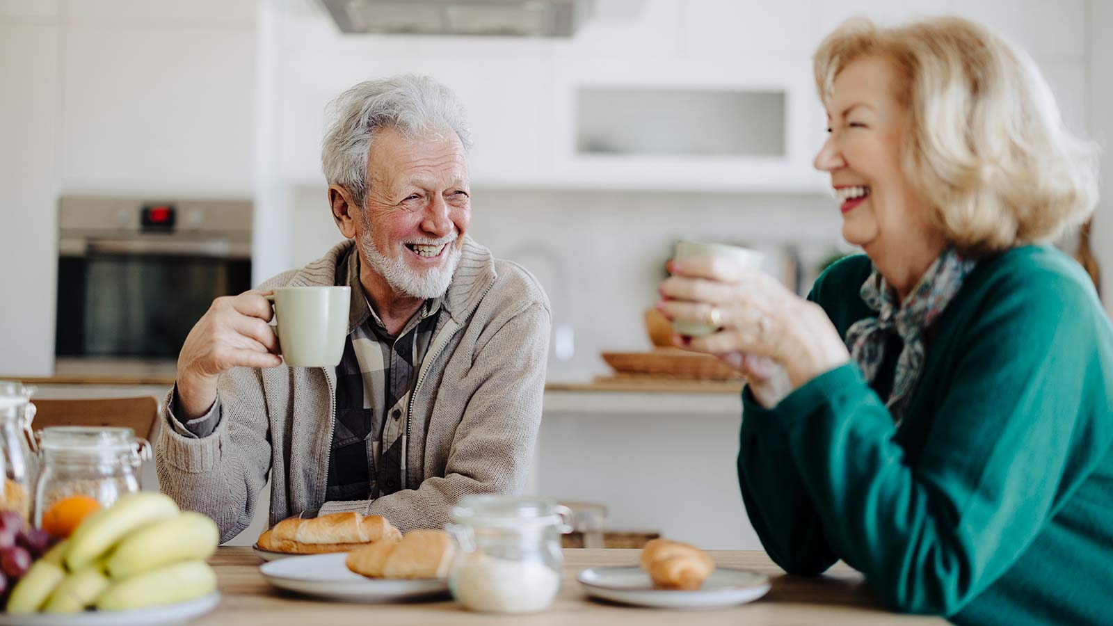 Older couple drinking coffee and smiling at the table.