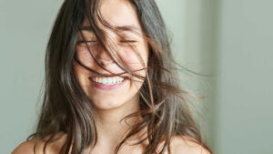 Girl smiling, showing her teeth with hair in her face.