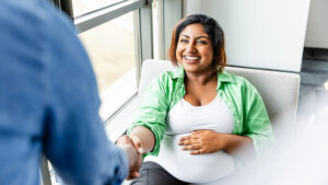 Young pregnant woman shaking hands and smiling.
