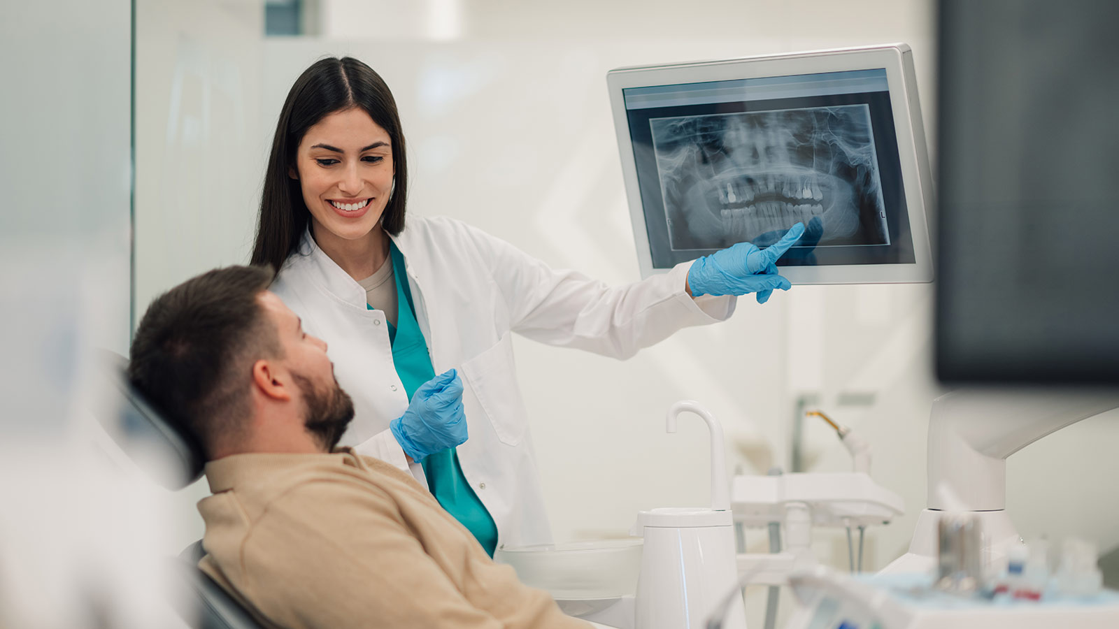 Dentist showing teeth x-ray to patient in modern clinic