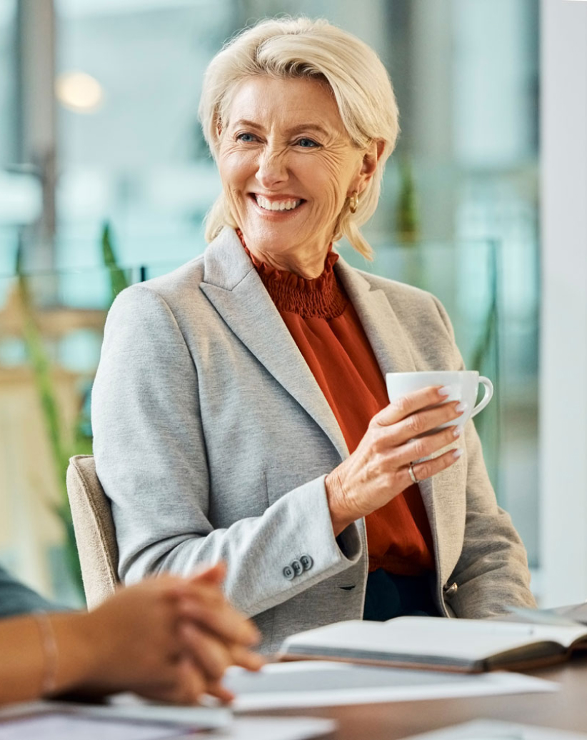 Two female colleagues sitting at a table, smiling and discussing business.