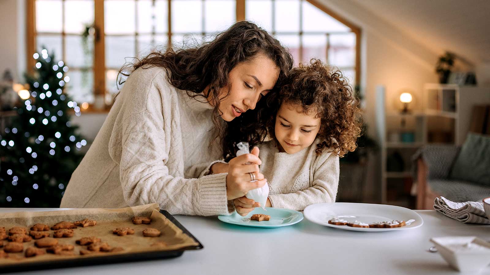 Mother and daughter baking and decorating cookies in the kitchen.