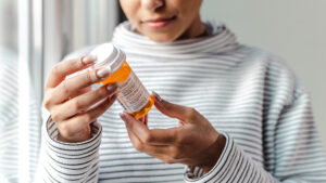 A female holding and looking at a prescription bottle.