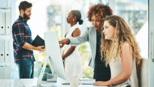 Employees in a work setting looking at a monitor.
