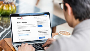 Man on laptop searching for a dental provider while drinking coffee.