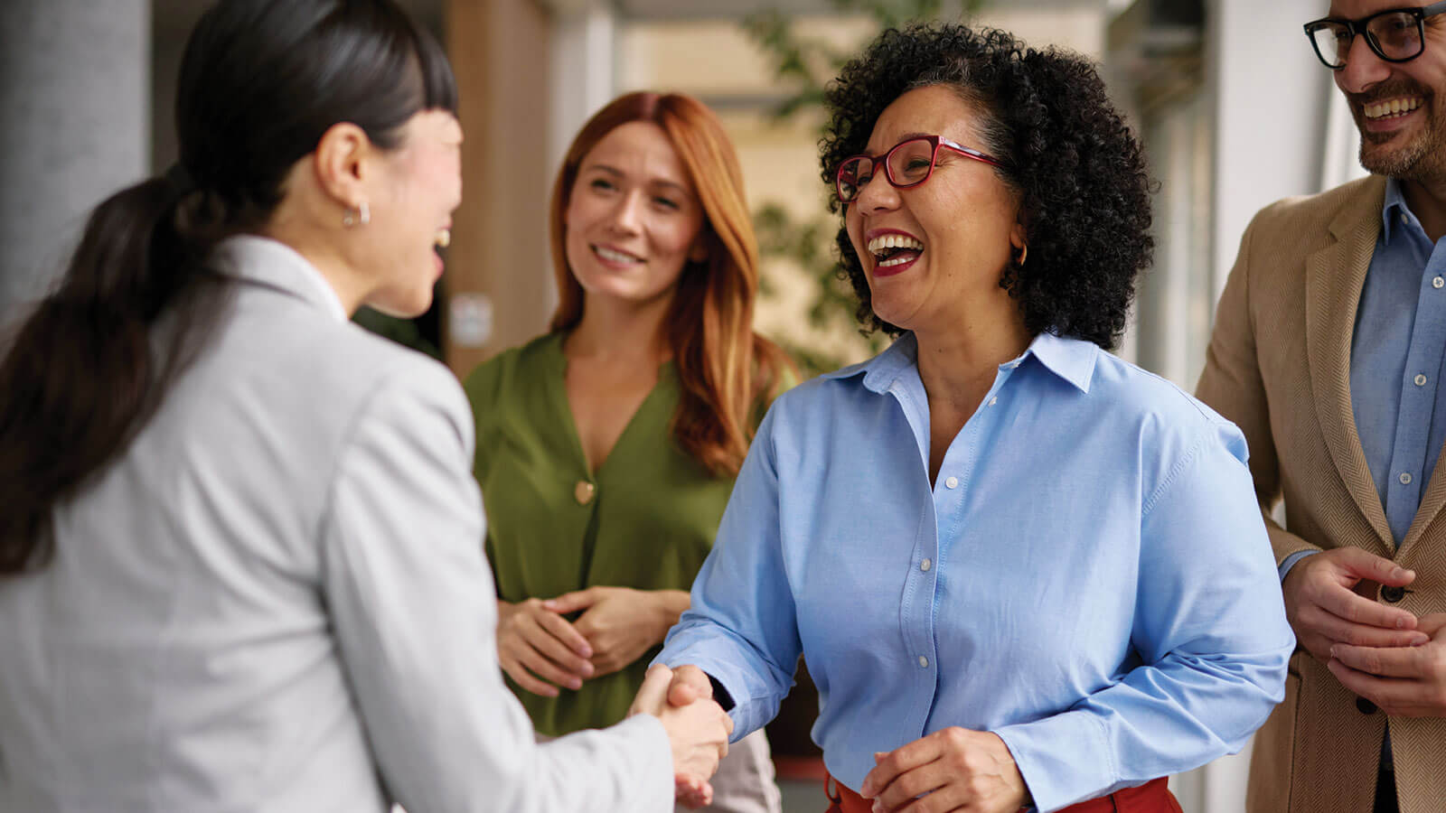 A professional, working woman meets the newest member of her team at work, laughing and shaking hands with her new employee. As she’s moved up in her career, the benefits of disability income insurance help protect her income.