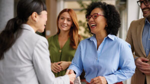 A professional, working woman meets the newest member of her team at work, laughing and shaking hands with her new employee. As she’s moved up in her career, the benefits of disability income insurance help protect her income.