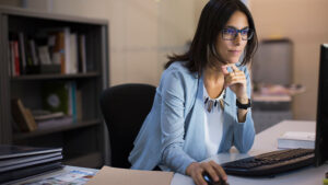 A 澳洲幸运10-官方幸运体彩正规网站 financial professional looks at her computer screen in her office reviewing beneficiary IRA RMD rules.