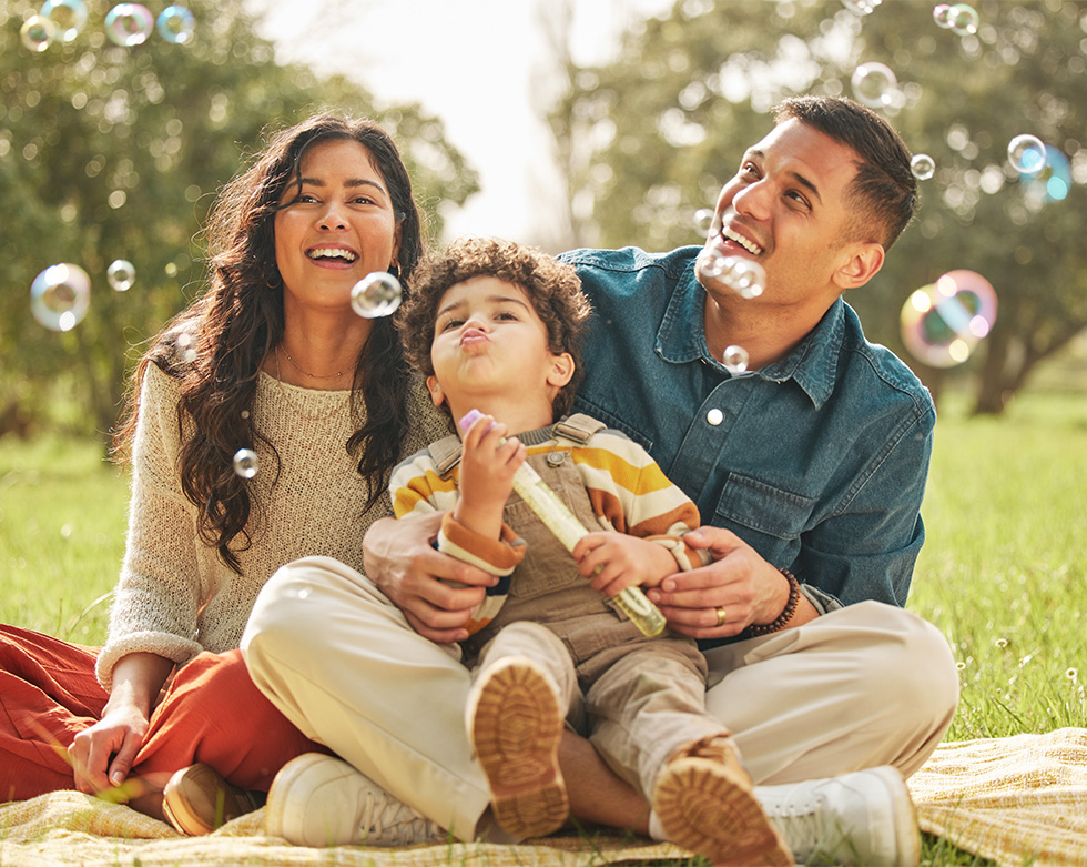 happy couple with child in the park blowing bubbles