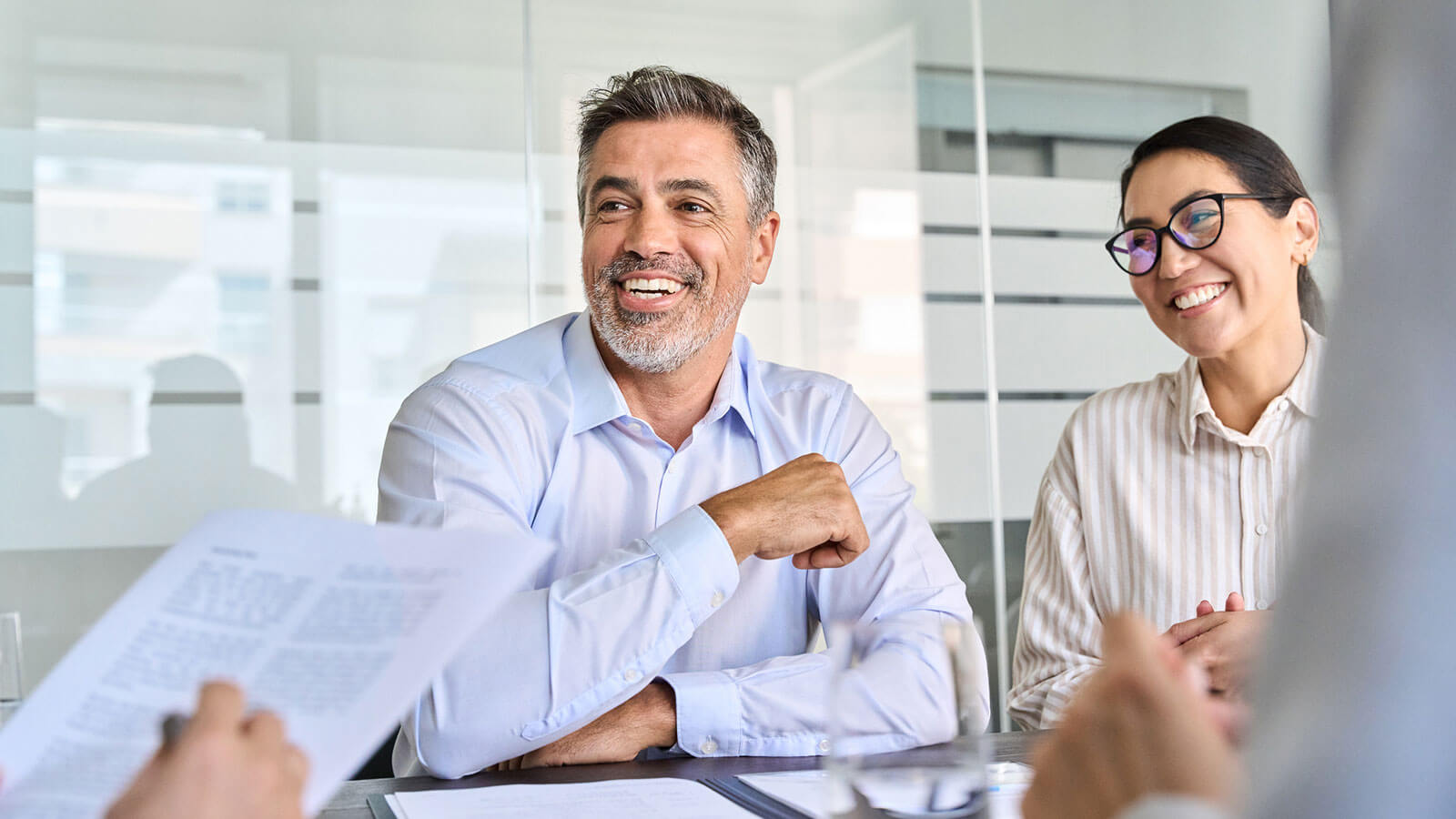 An independent financial professional smiles and laughs with his team during a meeting.