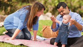 Parents with toddler child enjoying a picnic.