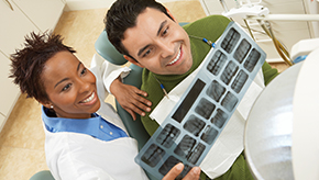 A dentist and her patient look at the patient's dental x-rays together